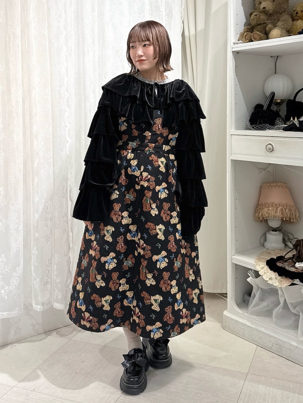 グレー系のニット/セーター、ブラック系のカーディガン/ボレロ、ブラック系のジャンパースカートを着用したレディースの秋コーディネートの2枚目の写真