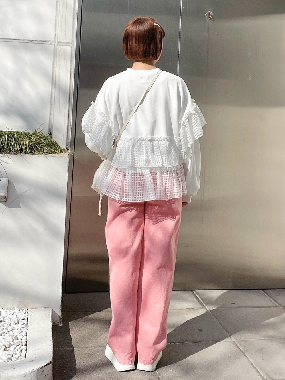 ホワイト系のスウェット、ピンク系のデニムパンツ、ホワイト系のショルダーバッグを着用したレディースの冬コーディネートの3枚目の写真