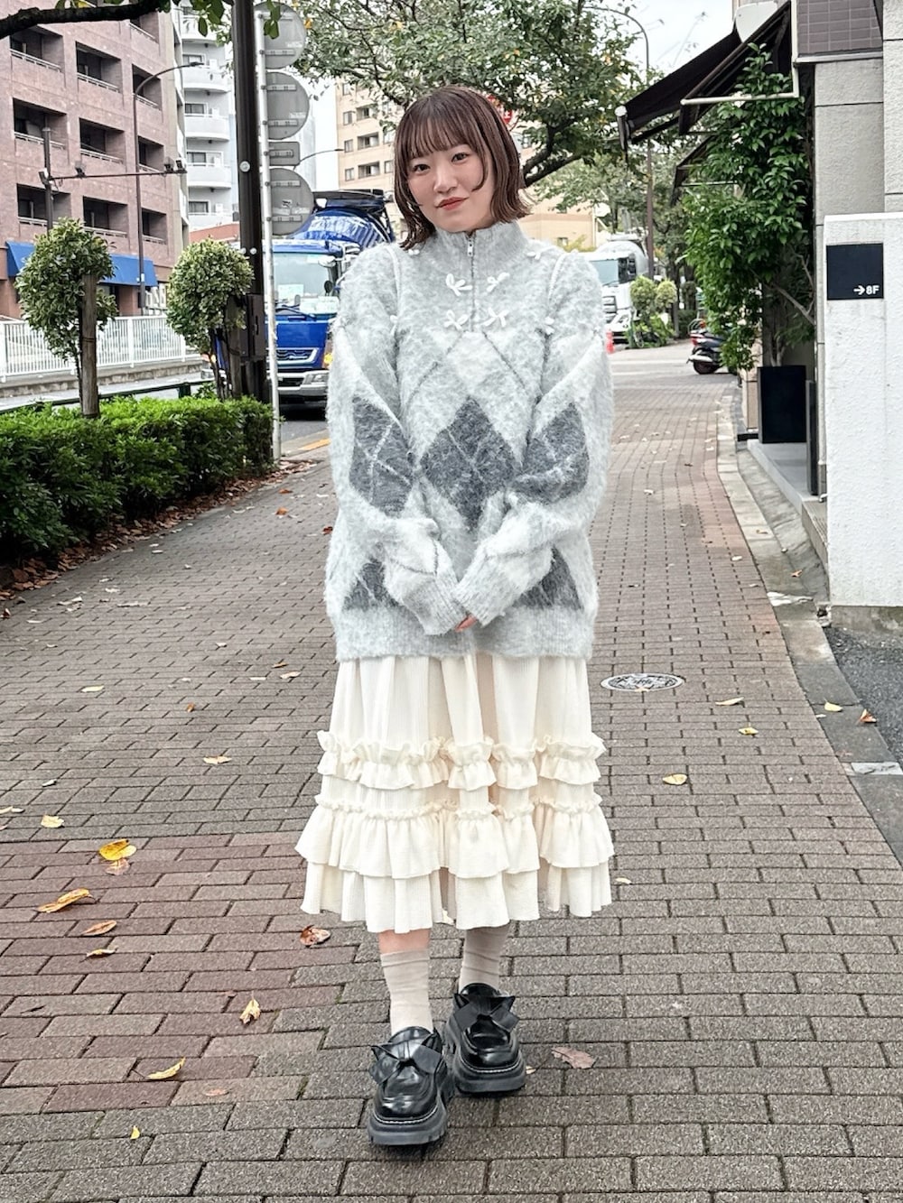 ホワイト系のスカート、グレー系のニット/セーター、ホワイト系のバックパック/リュックを着用したレディースの秋コーディネートの2枚目の写真