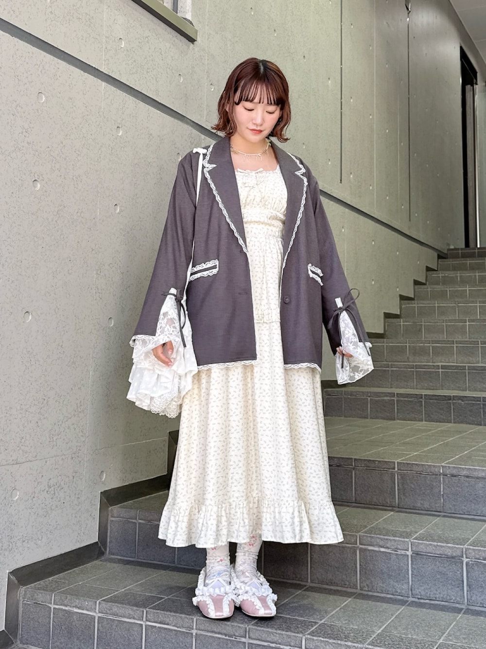 グレー系のテーラードジャケット、ベージュ系のワンピース、ホワイト系のショルダーバッグを着用したレディースの冬コーディネートの2枚目の写真