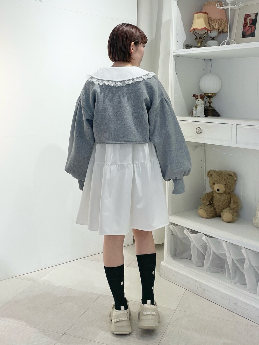 グレー系のカーディガン/ボレロ、ホワイト系のワンピース、ホワイト系のスニーカーを着用したレディースの冬コーディネートの3枚目の写真