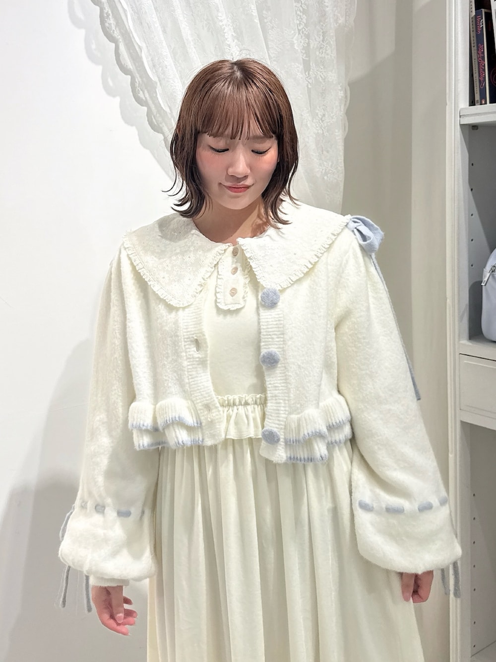 ホワイト系のワンピース、ホワイト系のカーディガン/ボレロ、ブルー系のハンドバッグを着用したレディースの秋コーディネートの5枚目の写真