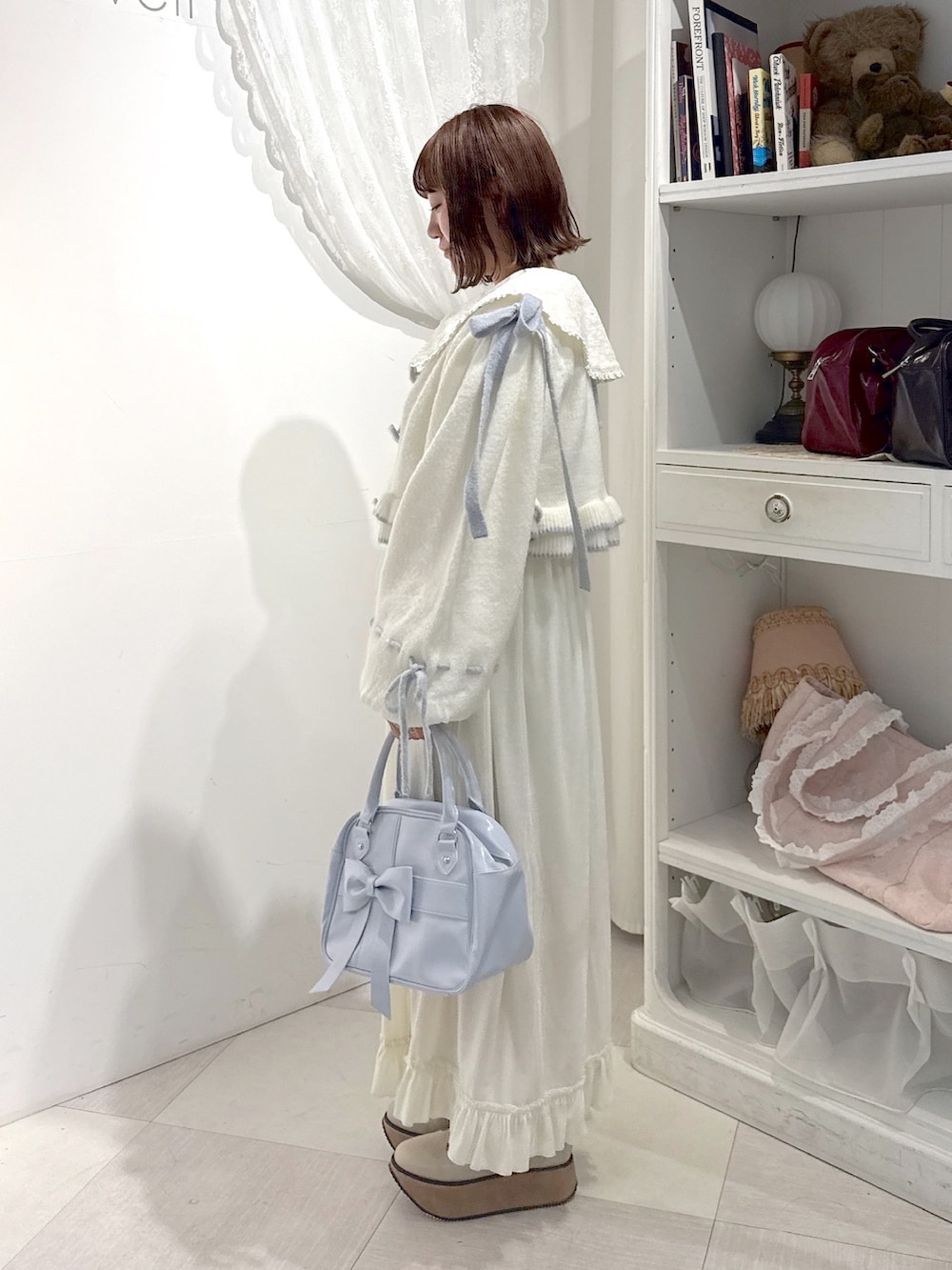 ホワイト系のワンピース、ホワイト系のカーディガン/ボレロ、ブルー系のハンドバッグを着用したレディースの秋コーディネートの3枚目の写真