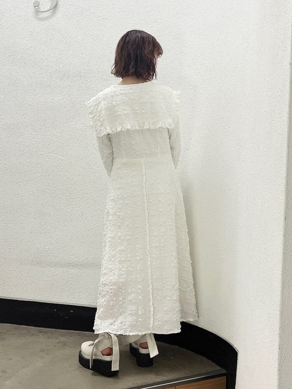 ホワイト系のワンピース、ベージュ系のトレンチコート、ホワイト系のパンプスを着用したレディースの冬コーディネートの7枚目の写真