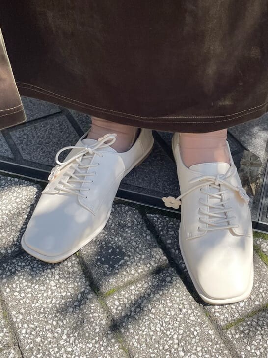 ホワイト系のニット/セーター、ホワイト系のその他シューズ、ベージュ系のスカートを着用したレディースの秋コーディネートの6枚目の写真