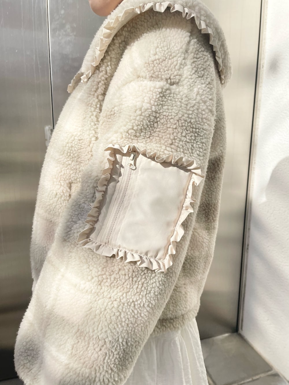 ホワイト系のスカート、ベージュ系のブルゾン、ホワイト系のニット/セーターを着用したレディースの冬コーディネートの9枚目の写真