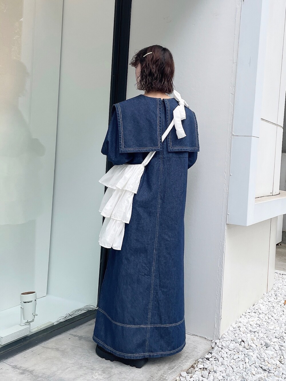 ホワイト系のトートバッグ、ベージュ系のブーツ、ブルー系のワンピースを着用したレディースの秋コーディネートの2枚目の写真