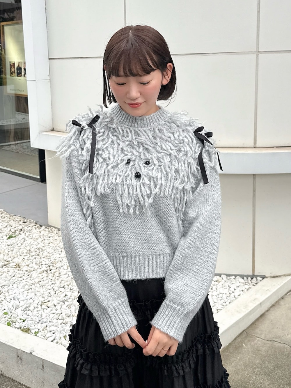 グレー系のニット/セーター、ブラック系のスカート、ブラック系のスニーカーを着用したレディースの夏コーディネートの5枚目の写真