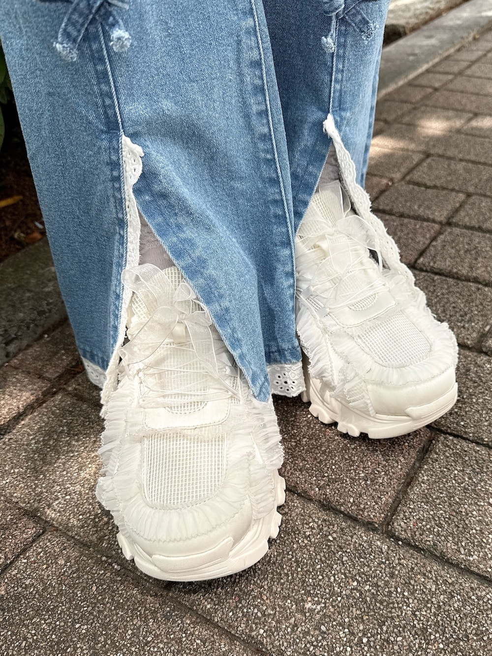 ブルー系のデニムパンツ、ホワイト系のスカート、ホワイト系のパーカーを着用したレディースの春コーディネートの9枚目の写真