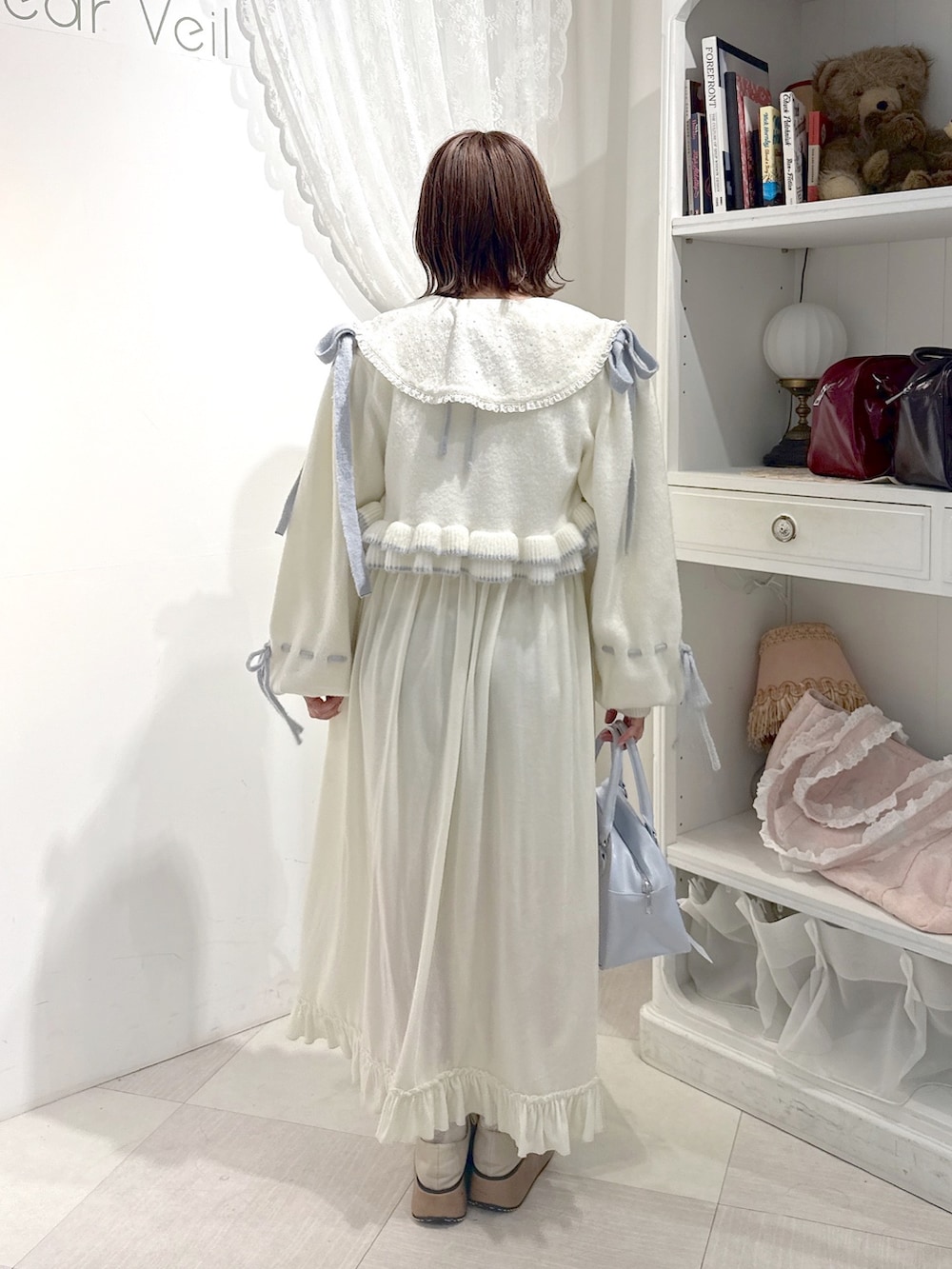ホワイト系のワンピース、ホワイト系のカーディガン/ボレロ、ブルー系のハンドバッグを着用したレディースの秋コーディネートの4枚目の写真