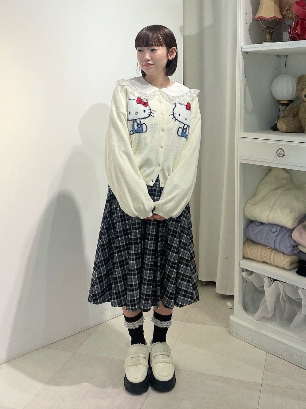ホワイト系のカーディガン/ボレロ、シルバー系のシャツ/ブラウス、ブラック系のスカートを着用したレディースの秋コーディネートの2枚目の写真