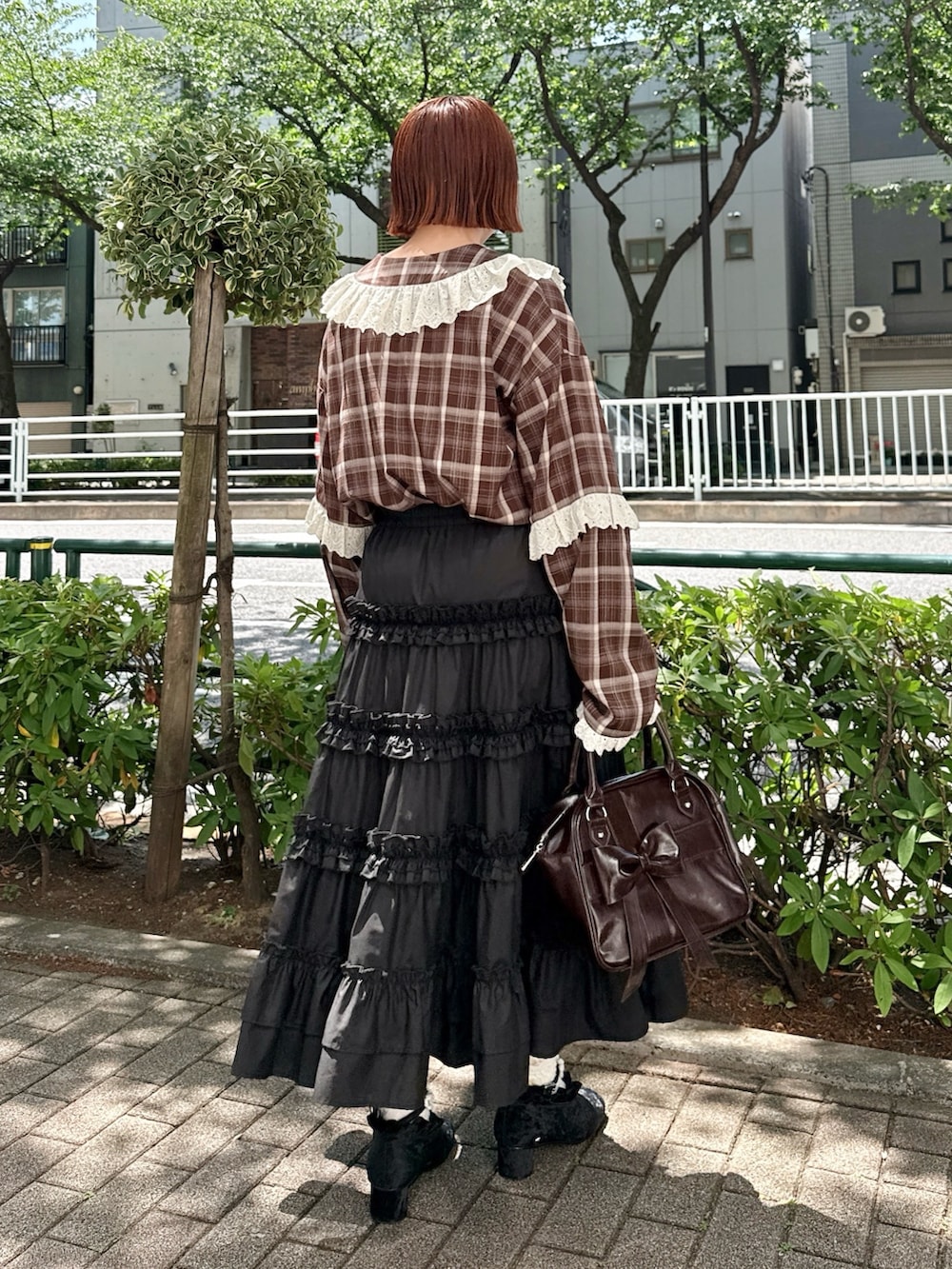 ブラウン系のハンドバッグ、ブラウン系のシャツ/ブラウス、ブラック系のスカートを着用したレディースの春コーディネートの2枚目の写真