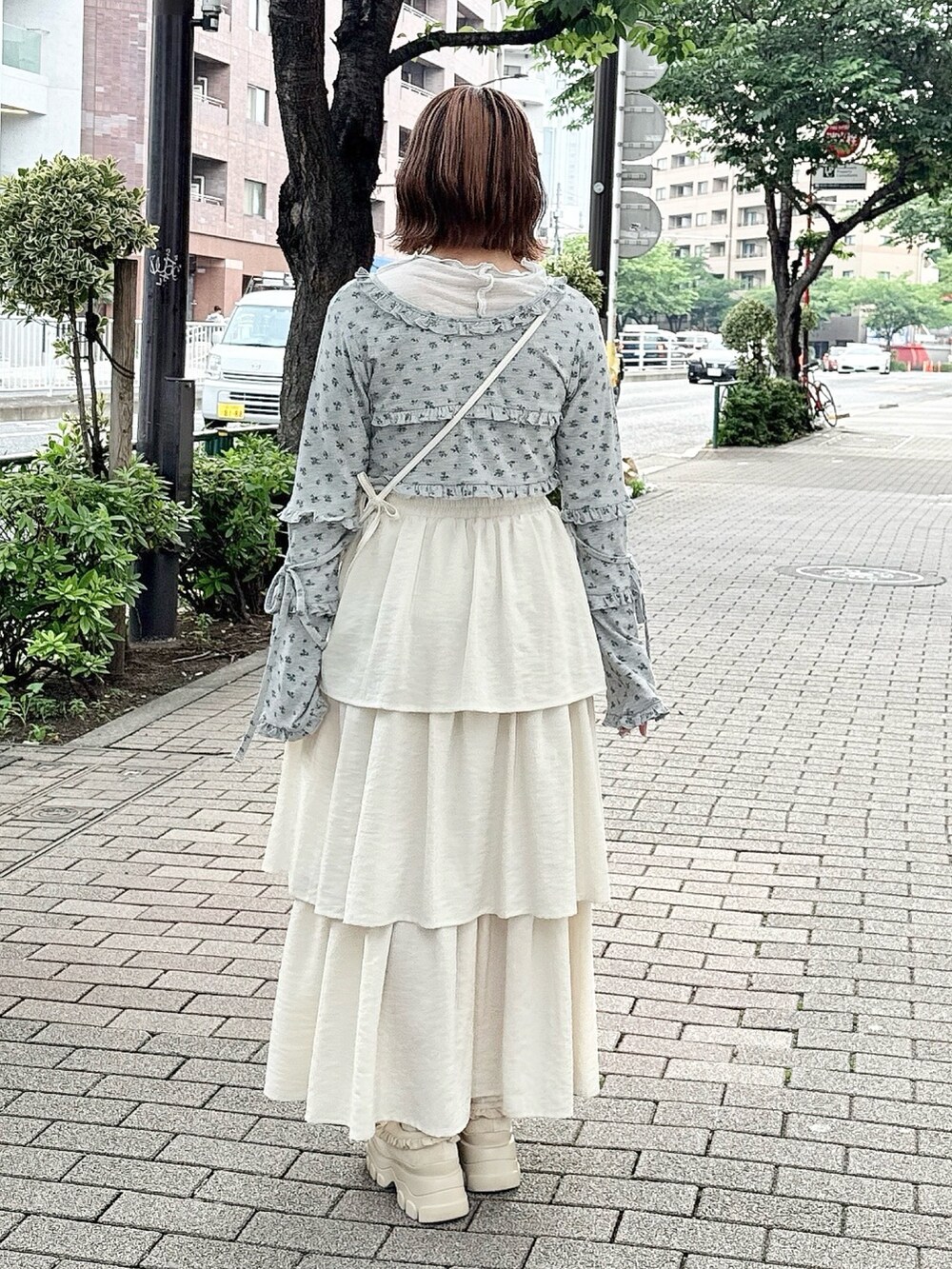 グレー系のカーディガン/ボレロ、ホワイト系のスカート、ホワイト系のショルダーバッグを着用したレディースの夏コーディネートの2枚目の写真