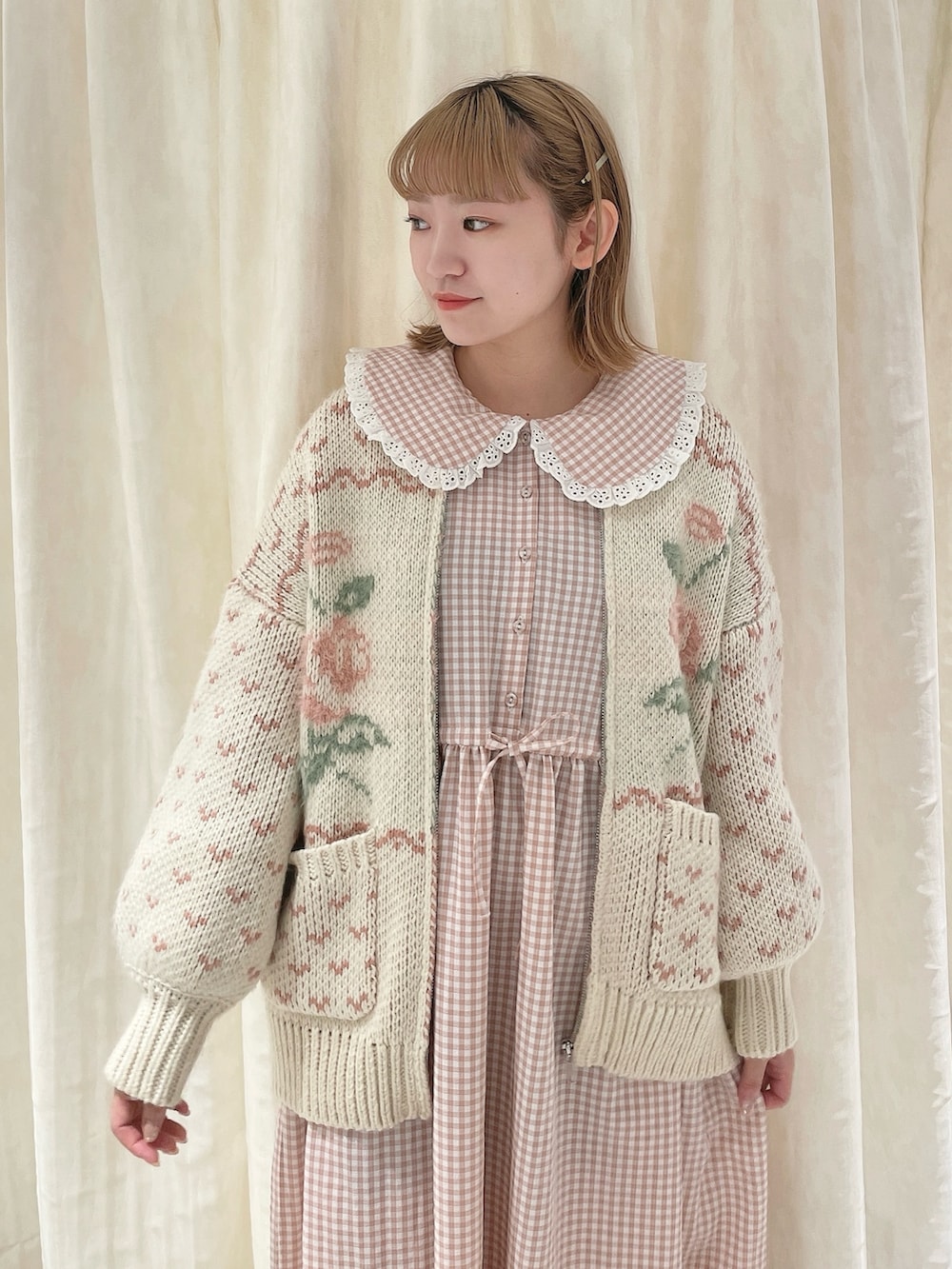 ピンク系のカーディガン/ボレロ、ピンク系のワンピース、ホワイト系のスニーカーを着用したレディースの冬コーディネートの4枚目の写真