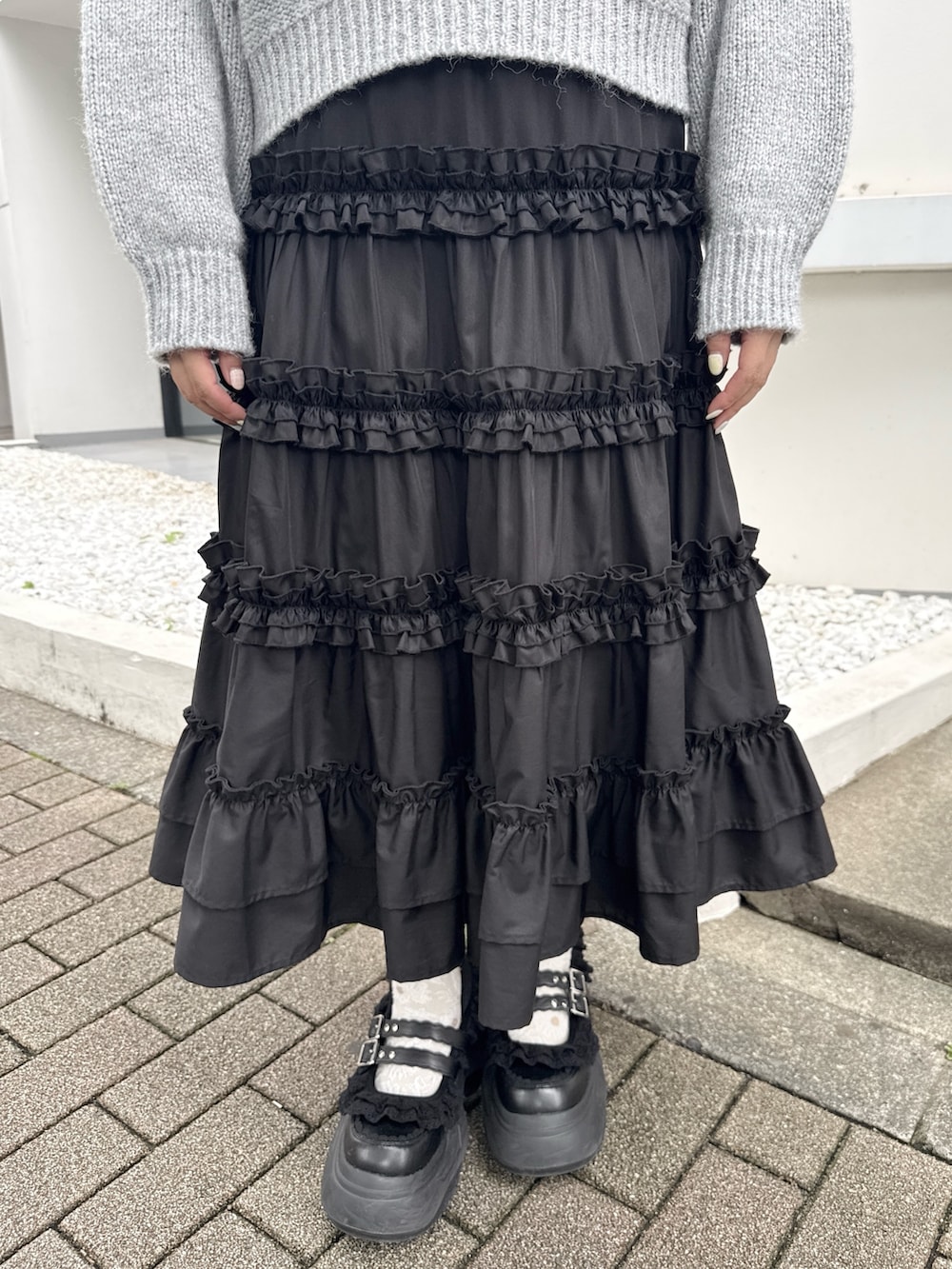 グレー系のニット/セーター、ブラック系のスカート、ブラック系のスニーカーを着用したレディースの夏コーディネートの7枚目の写真