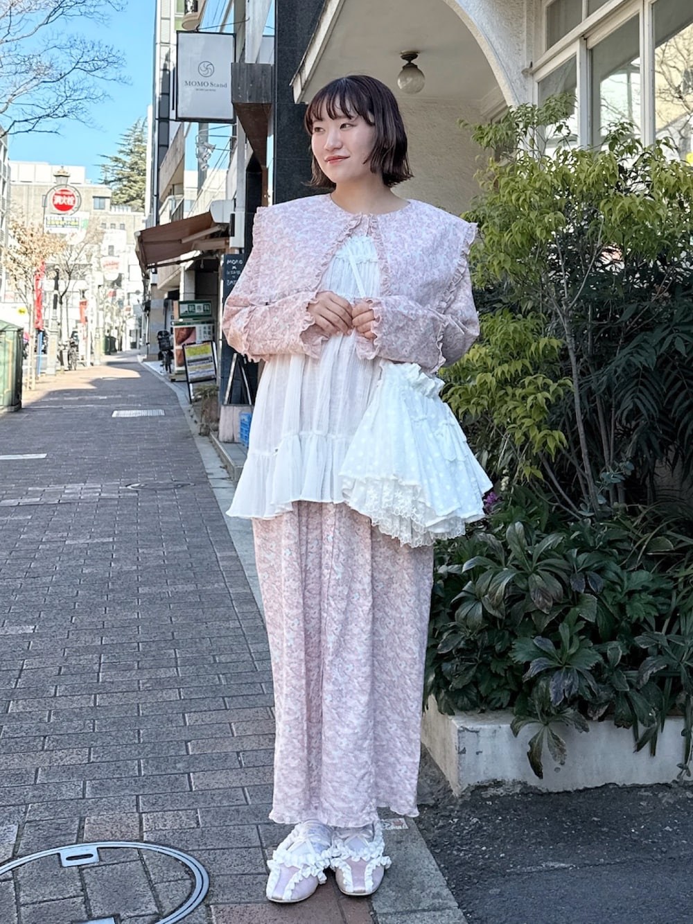 ピンク系のワンピース、ホワイト系のショルダーバッグ、ホワイト系のチュニックを着用したレディースの冬コーディネートの2枚目の写真