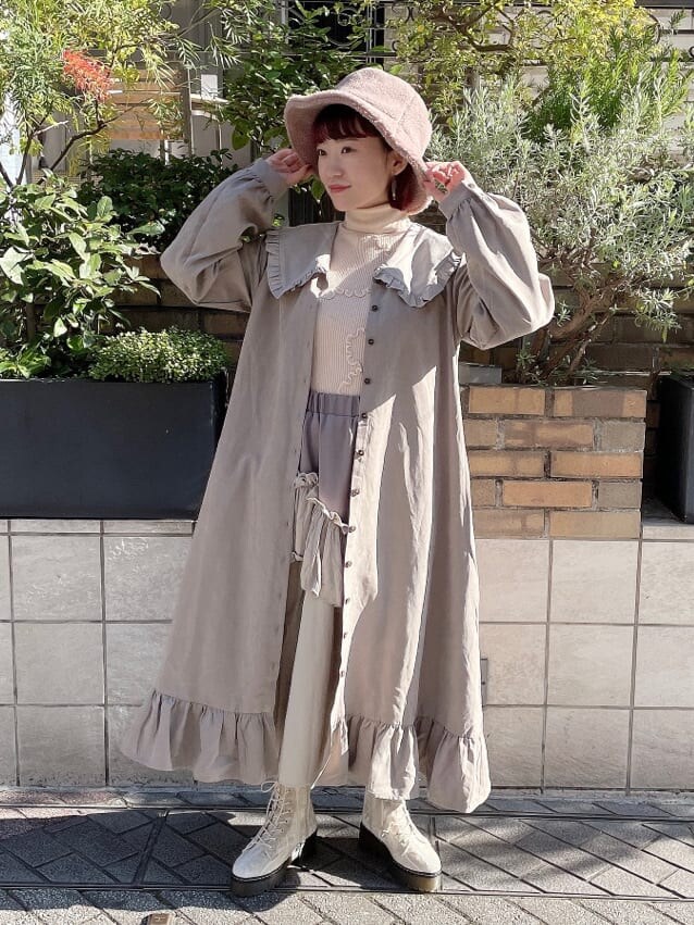 ホワイト系のニット/セーター、ベージュ系のスカート、ホワイト系のブーツを着用したレディースの冬コーディネートの2枚目の写真