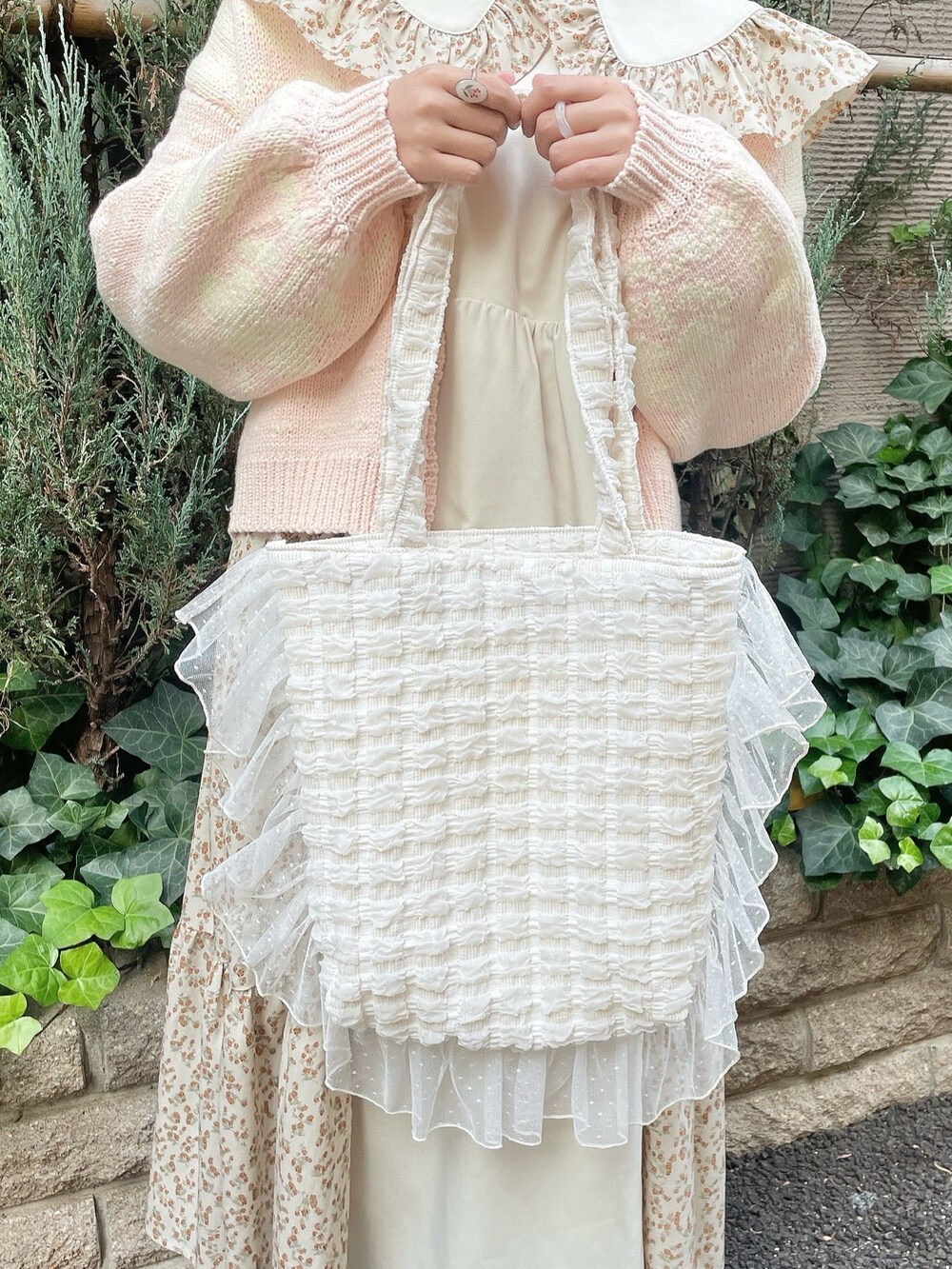 ベージュ系のワンピース、ピンク系のカーディガン/ボレロ、ホワイト系のトートバッグを着用したレディースの冬コーディネートの6枚目の写真