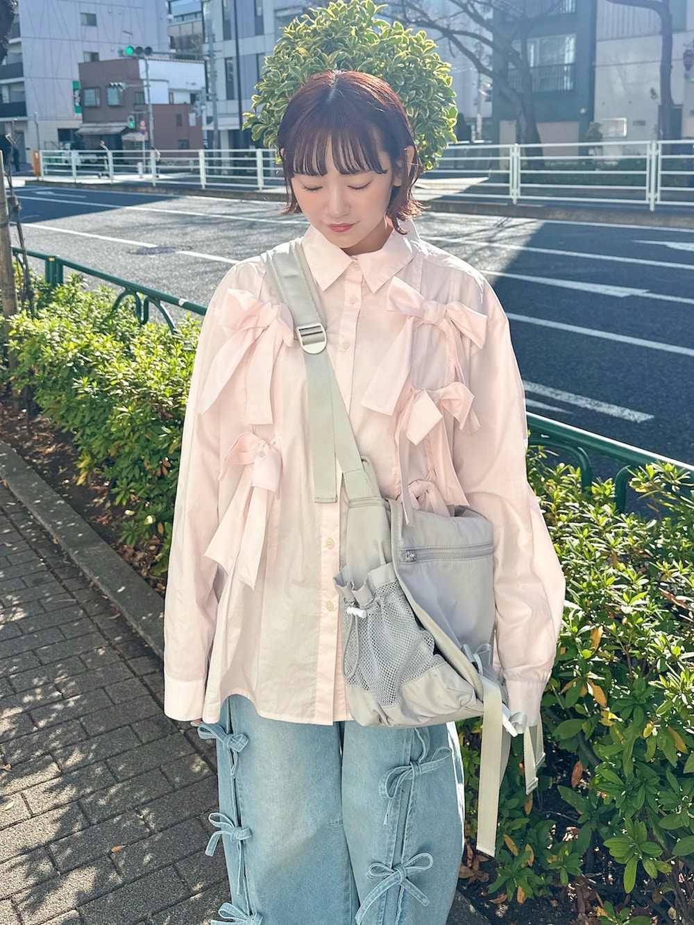 ピンク系のシャツ/ブラウス、グレー系のメッセンジャーバッグ、ブルー系のデニムパンツを着用したレディースの冬コーディネートの3枚目の写真