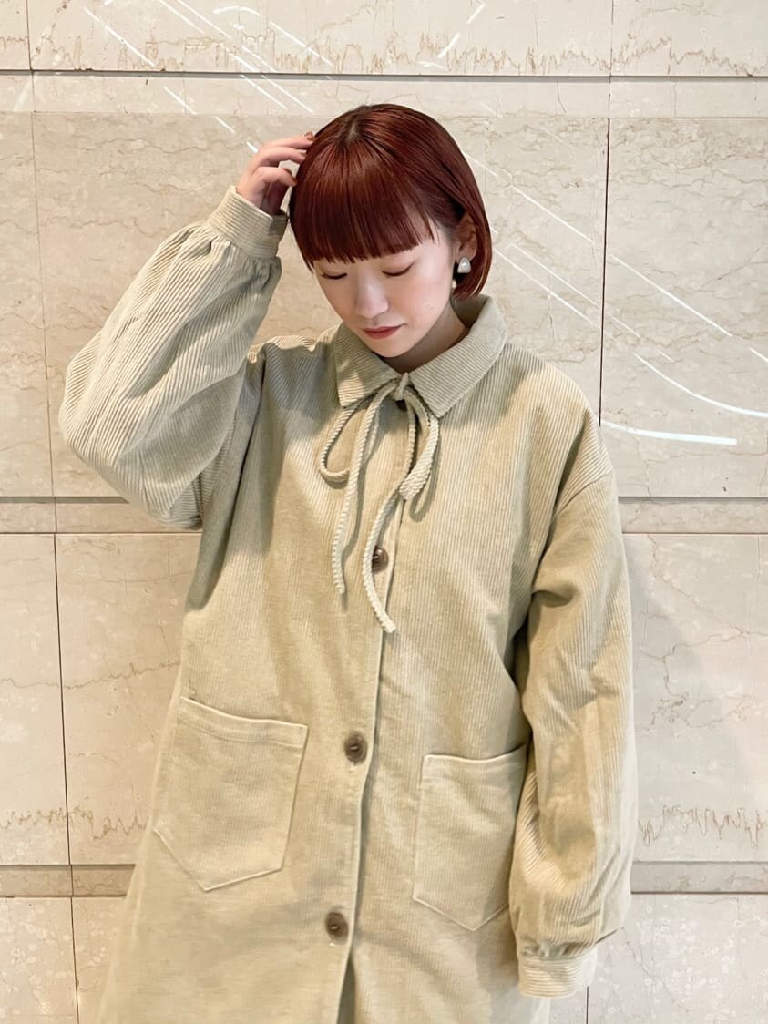 レッド系のワンピース、ブラック系のその他シューズ、ベージュ系のステンカラーコートを着用したレディースの秋コーディネートの3枚目の写真