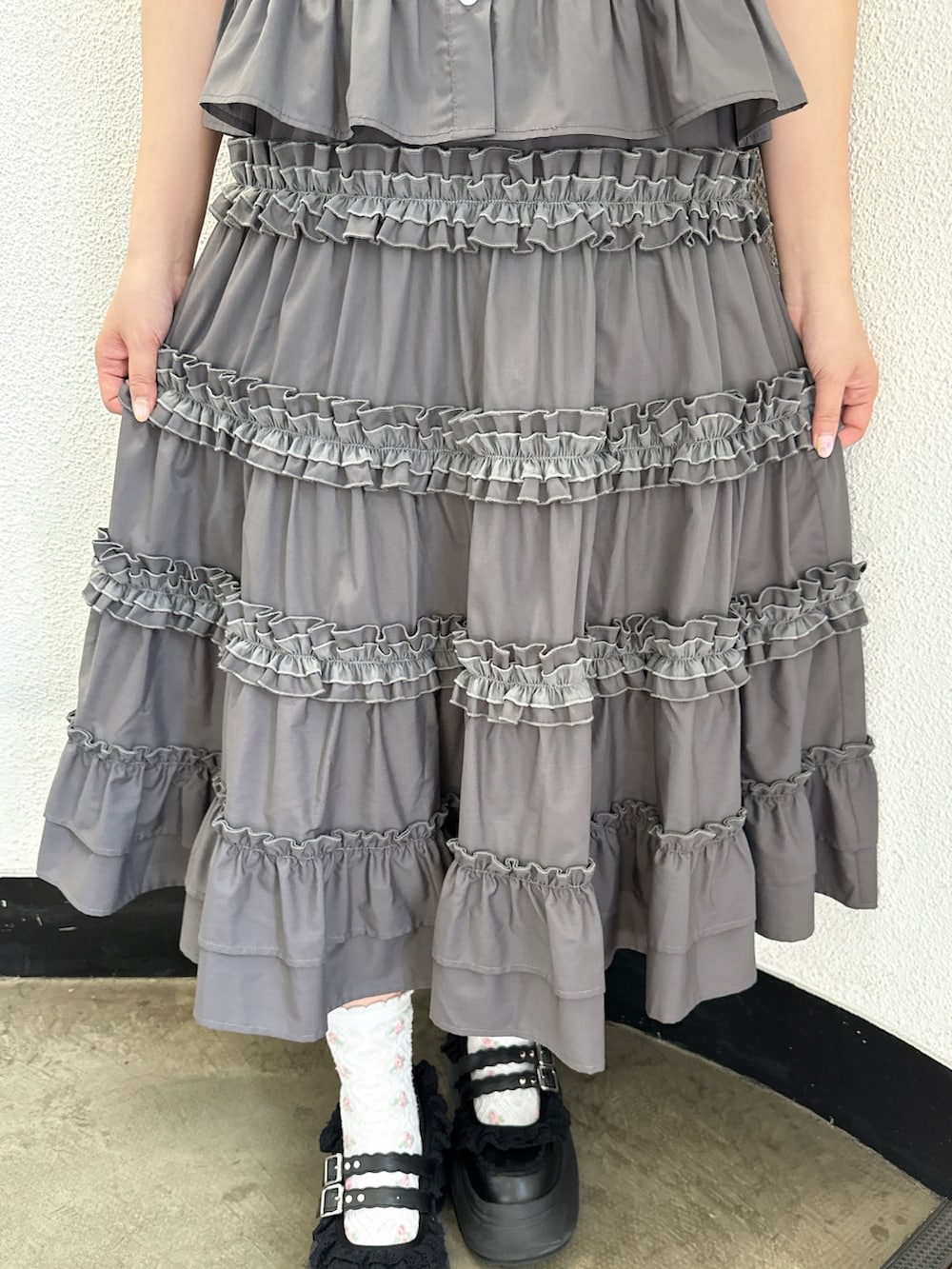 グレー系のシャツ/ブラウス、グレー系のスカート、ブラック系のスニーカーを着用したレディースの春コーディネートの6枚目の写真
