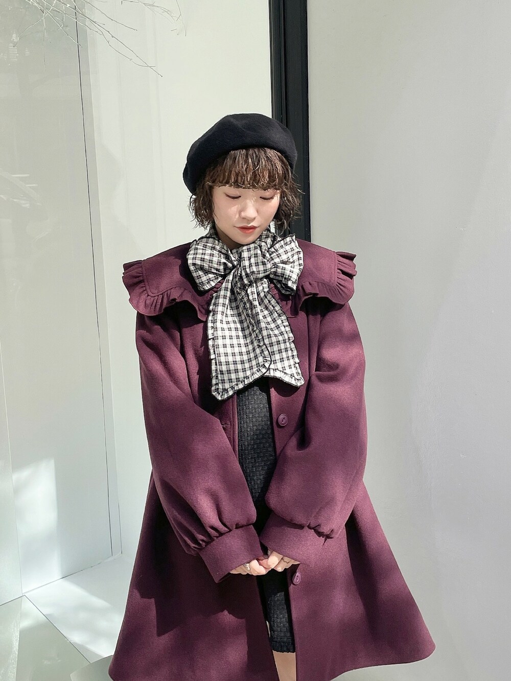 ブラック系のスニーカー、レッド系のチェスターコート、ブラック系のジャンパースカートを着用したレディースの秋コーディネートの3枚目の写真