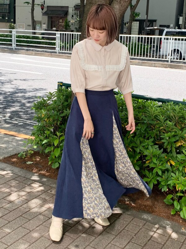 ホワイト系のパンプス、ベージュ系のシャツ/ブラウス、ブルー系のスカートを着用したレディースの春コーディネートの2枚目の写真