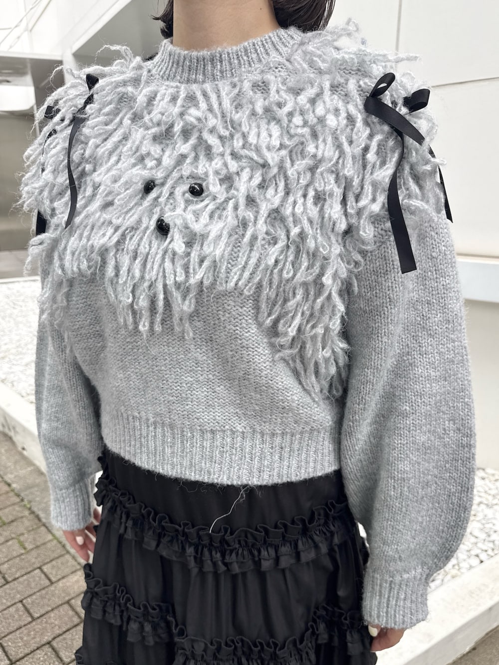 グレー系のニット/セーター、ブラック系のスカート、ブラック系のスニーカーを着用したレディースの夏コーディネートの6枚目の写真