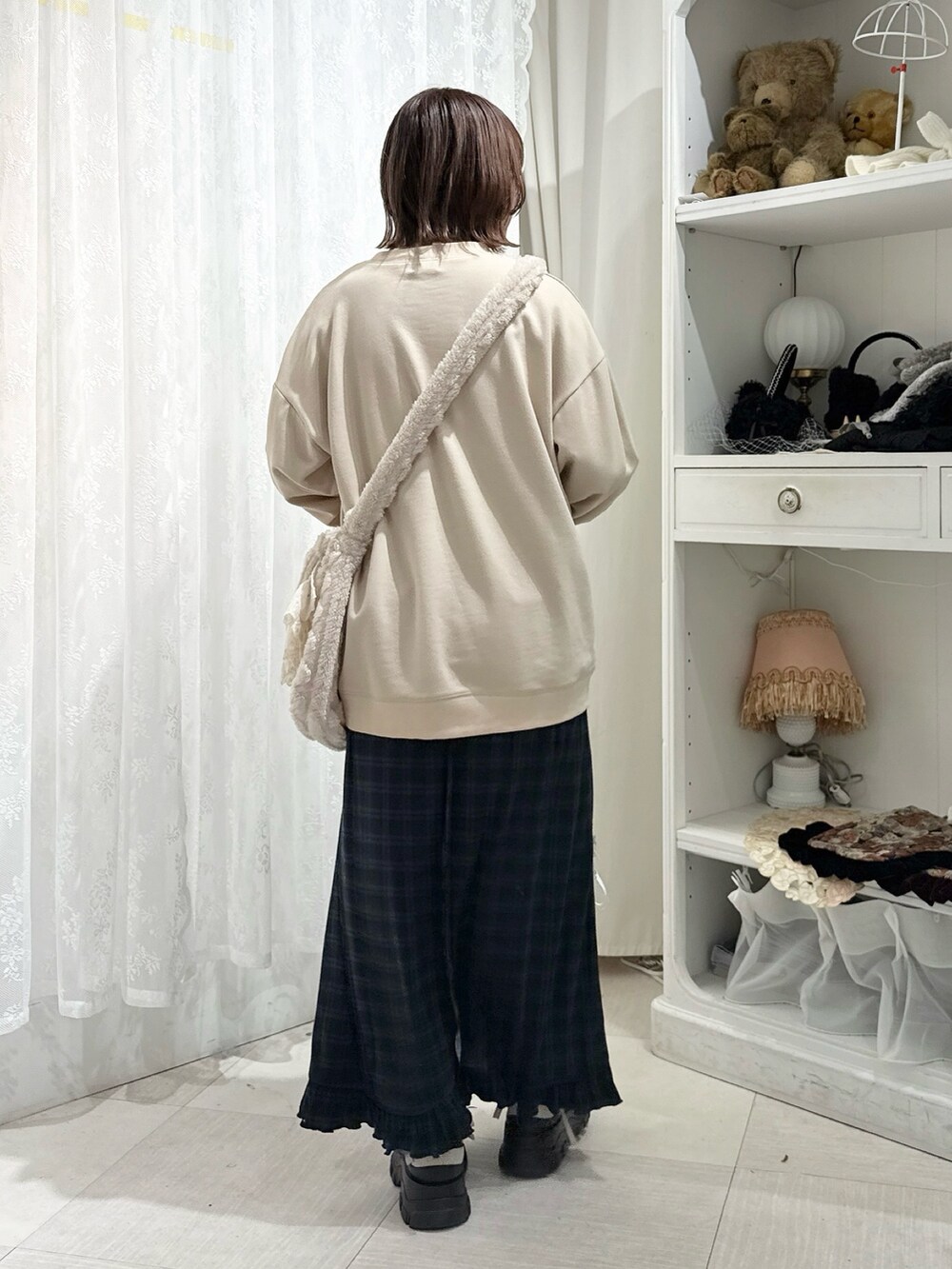 ベージュ系のスウェット、ベージュ系のショルダーバッグ、グリーン系のスカートを着用したレディースの秋コーディネートの4枚目の写真