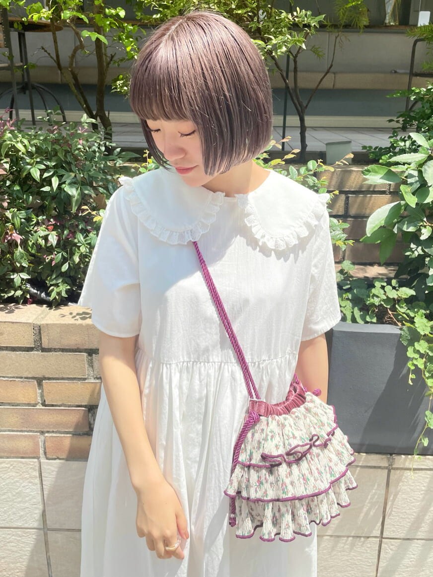 ホワイト系のワンピース、ホワイト系のパンプス、パープル系のハンドバッグを着用したレディースの夏コーディネートの4枚目の写真