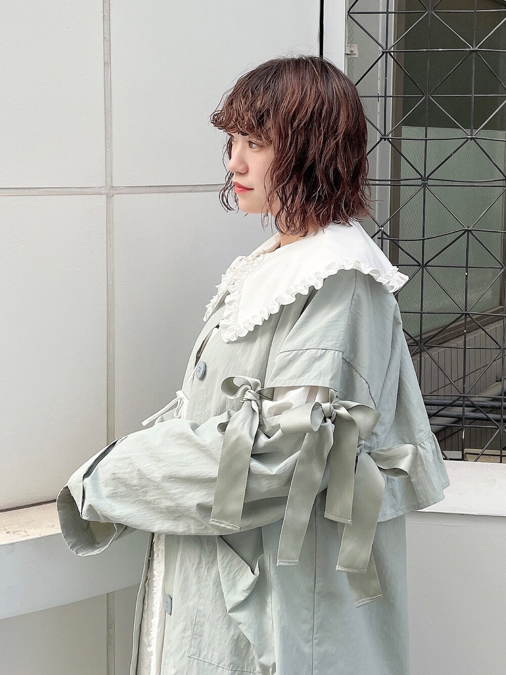 ブルー系のトレンチコート、ホワイト系のシャツ/ブラウス、ホワイト系のパンプスを着用したレディースの秋コーディネートの6枚目の写真