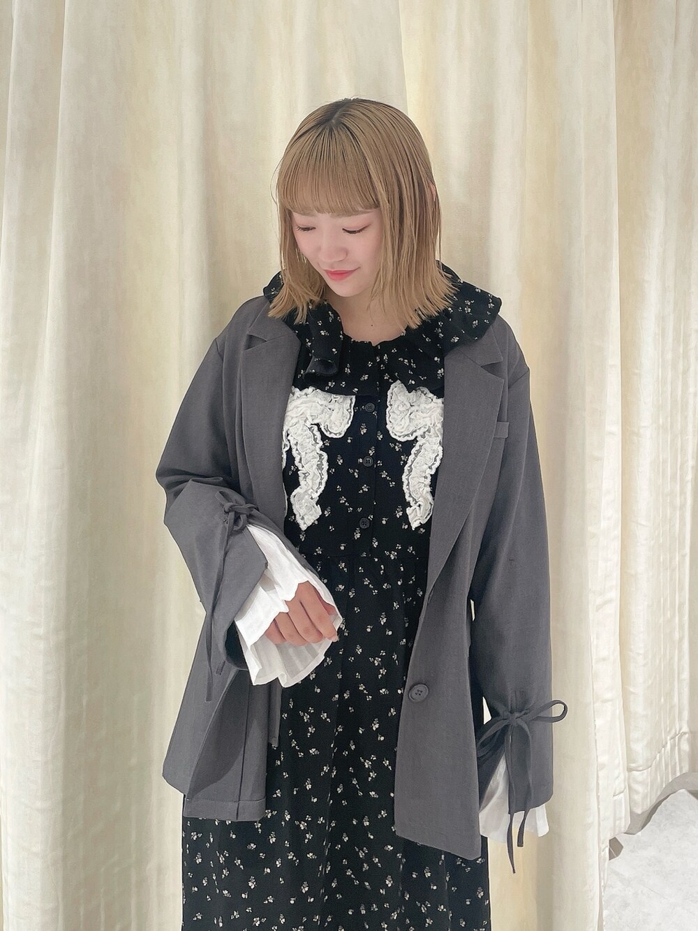 ブラック系のワンピース、グレー系のテーラードジャケット、ブラック系のスニーカーを着用したレディースの冬コーディネートの4枚目の写真