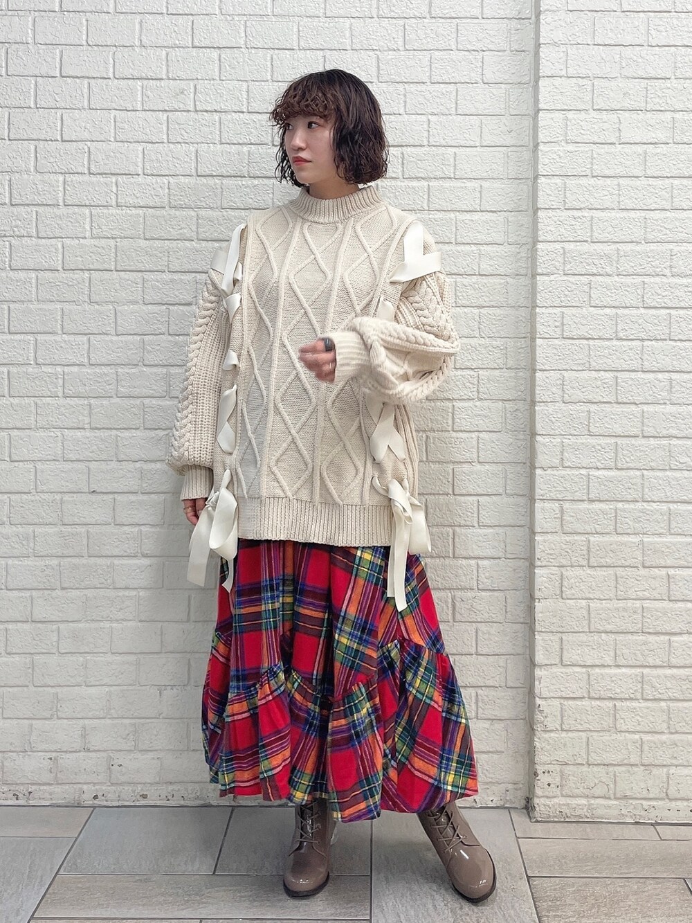 ホワイト系のニット/セーター、レッド系のスカート、ベージュ系のブーツを着用したレディースの冬コーディネートの2枚目の写真