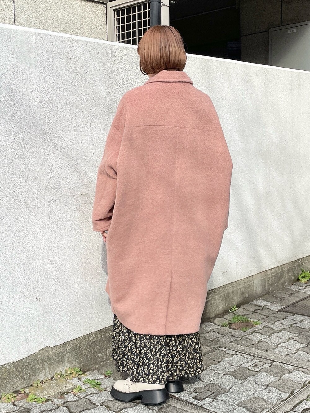 ピンク系のチェスターコート、ブラック系のスカート、グレー系のシャツ/ブラウスを着用したレディースの冬コーディネートの3枚目の写真