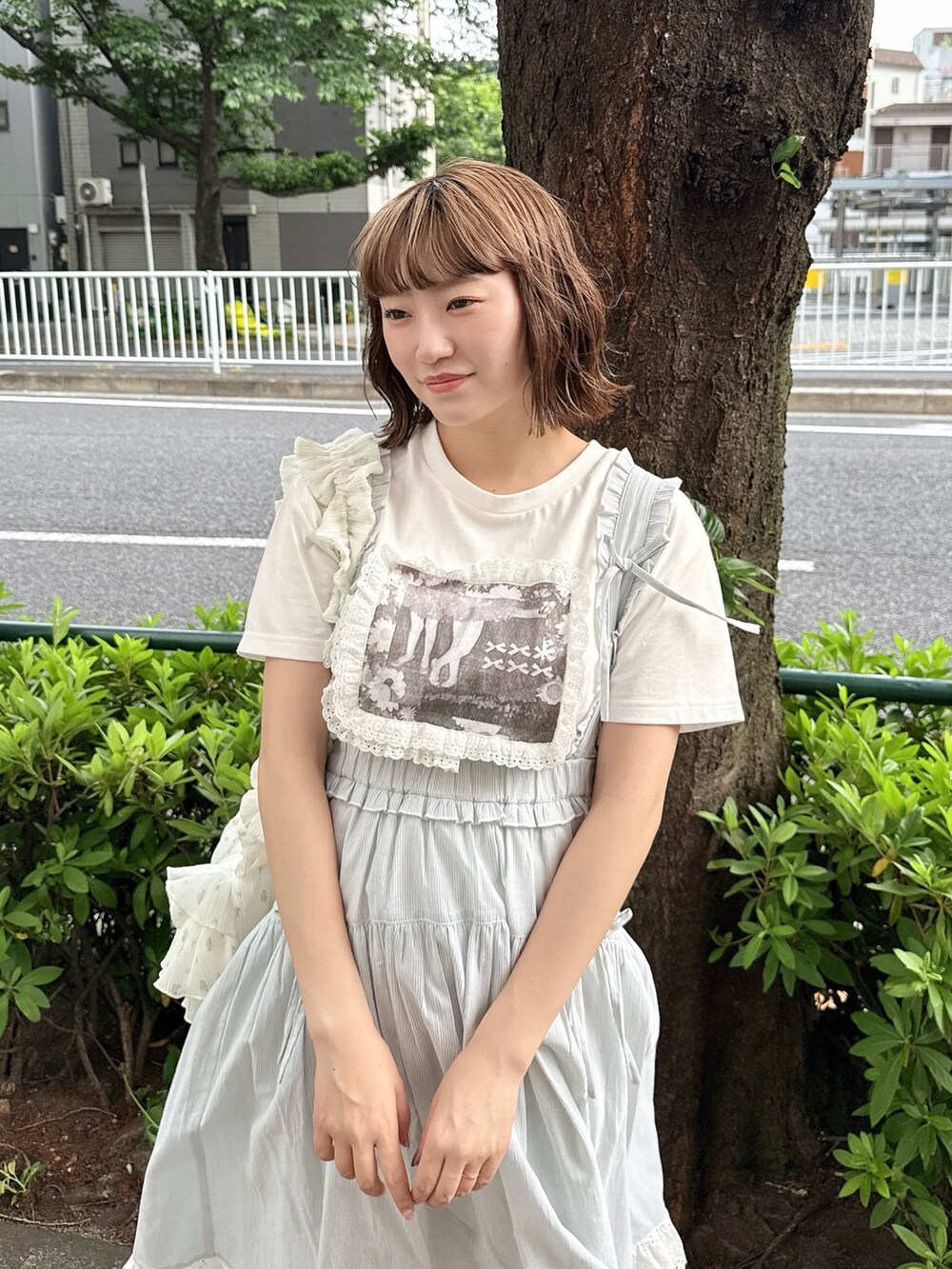 ホワイト系のTシャツ/カットソー、グリーン系のジャンパースカート、ホワイト系のショルダーバッグを着用したレディースの春コーディネートの3枚目の写真
