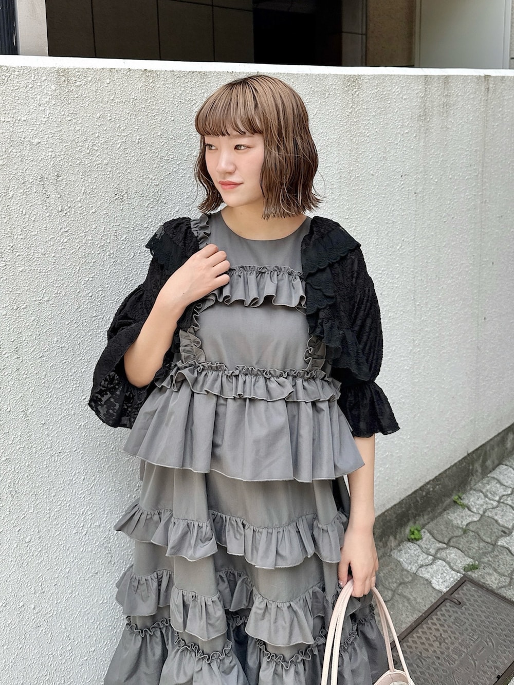 グレー系のワンピース、ブラック系のカーディガン/ボレロ、ピンク系のハンドバッグを着用したレディースの春コーディネートの6枚目の写真