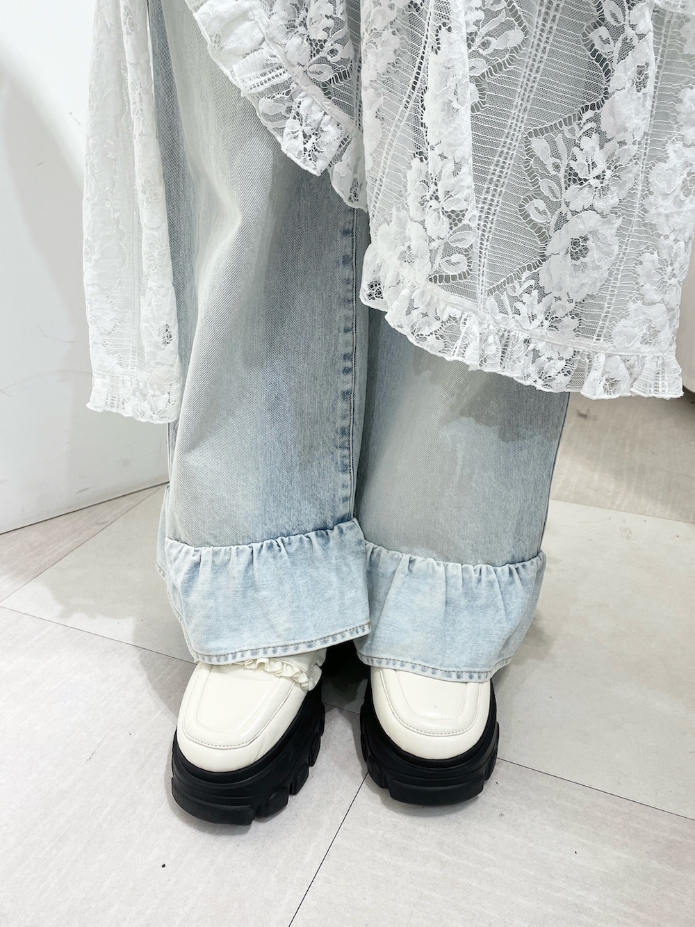 ホワイト系のニット/セーター、ブルー系のデニムパンツ、ホワイト系のスカートを着用したレディースの秋コーディネートの7枚目の写真