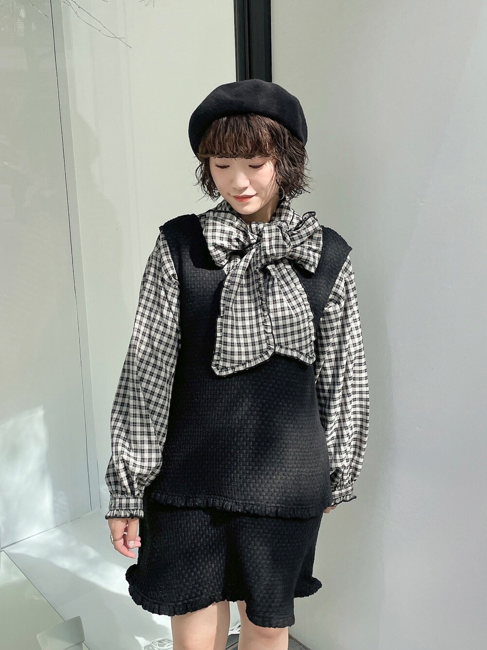 ブラック系のスニーカー、レッド系のチェスターコート、ブラック系のジャンパースカートを着用したレディースの秋コーディネートの7枚目の写真