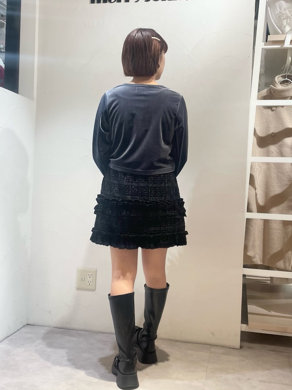 ブラック系のスカート、ブルー系のカーディガン/ボレロ、ブラック系のブーツを着用したレディースの冬コーディネートの3枚目の写真