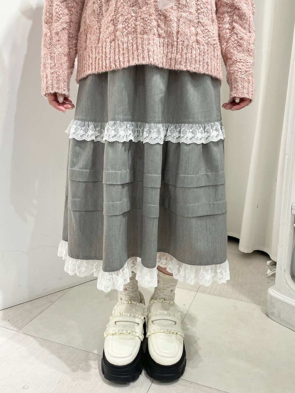 グレー系のスカート、ピンク系のニット/セーター、ホワイト系のローファーを着用したレディースの秋コーディネートの7枚目の写真