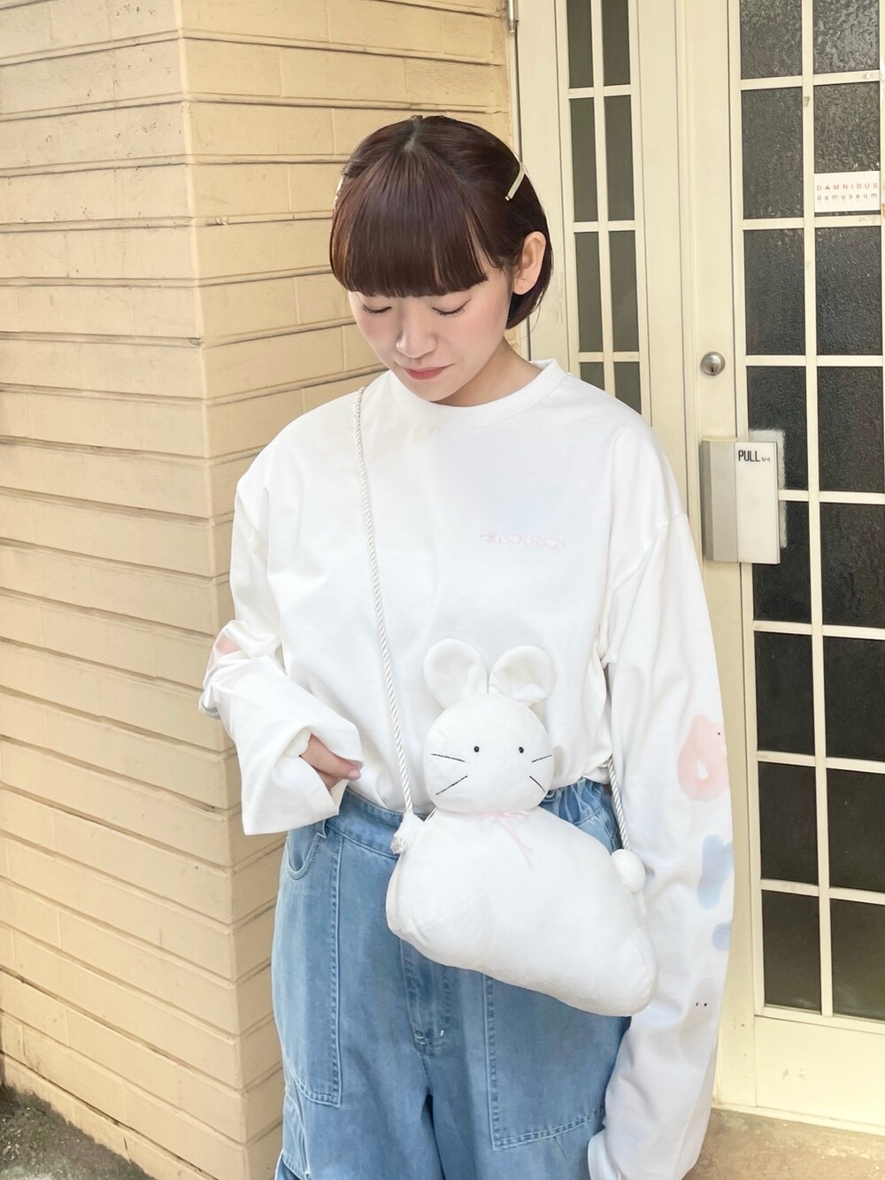 ホワイト系のTシャツ/カットソー、ホワイト系のショルダーバッグ、ブルー系のデニムパンツを着用したレディースの冬コーディネートの4枚目の写真