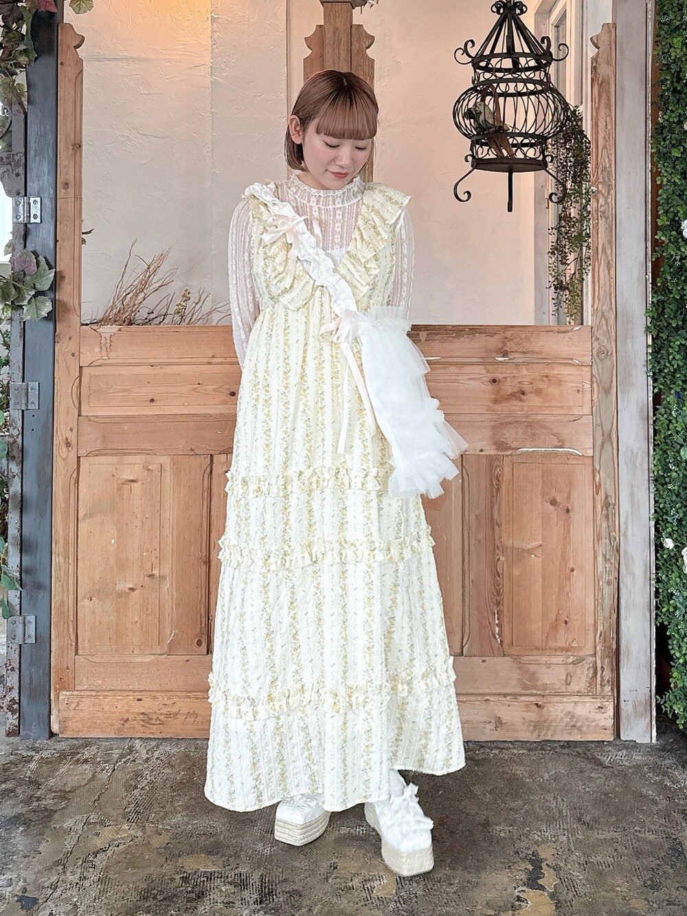 イエロー系のワンピース、ホワイト系のTシャツ/カットソー、ホワイト系のトートバッグを着用したレディースの春コーディネートの2枚目の写真