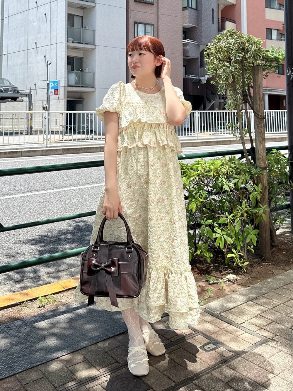 ブラウン系のハンドバッグ、イエロー系のワンピース、ホワイト系のバレエシューズを着用したレディースの春コーディネートの2枚目の写真