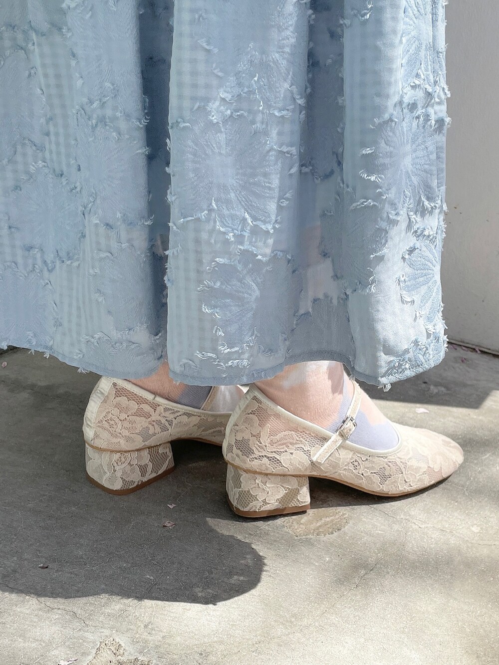 ブルー系のスカート、ホワイト系のニット/セーター、ホワイト系のパンプスを着用したレディースの春コーディネートの6枚目の写真