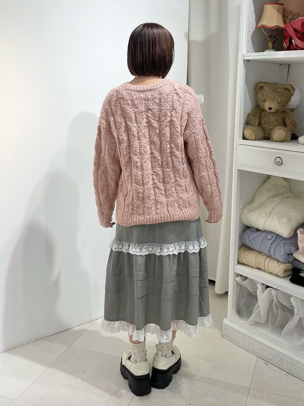 グレー系のスカート、ピンク系のニット/セーター、ホワイト系のローファーを着用したレディースの秋コーディネートの3枚目の写真