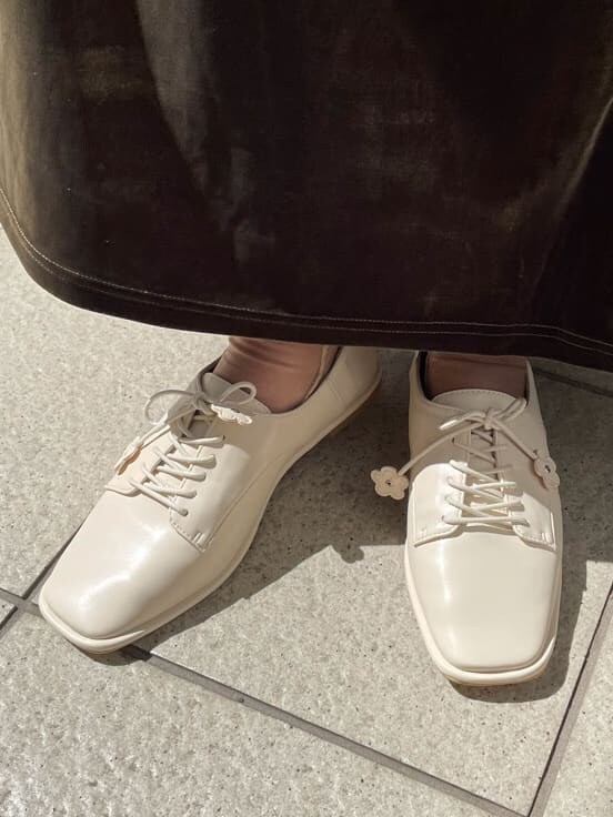 グリーン系のチェスターコート、ホワイト系のその他シューズ、ベージュ系のスカートを着用したレディースの秋コーディネートの7枚目の写真