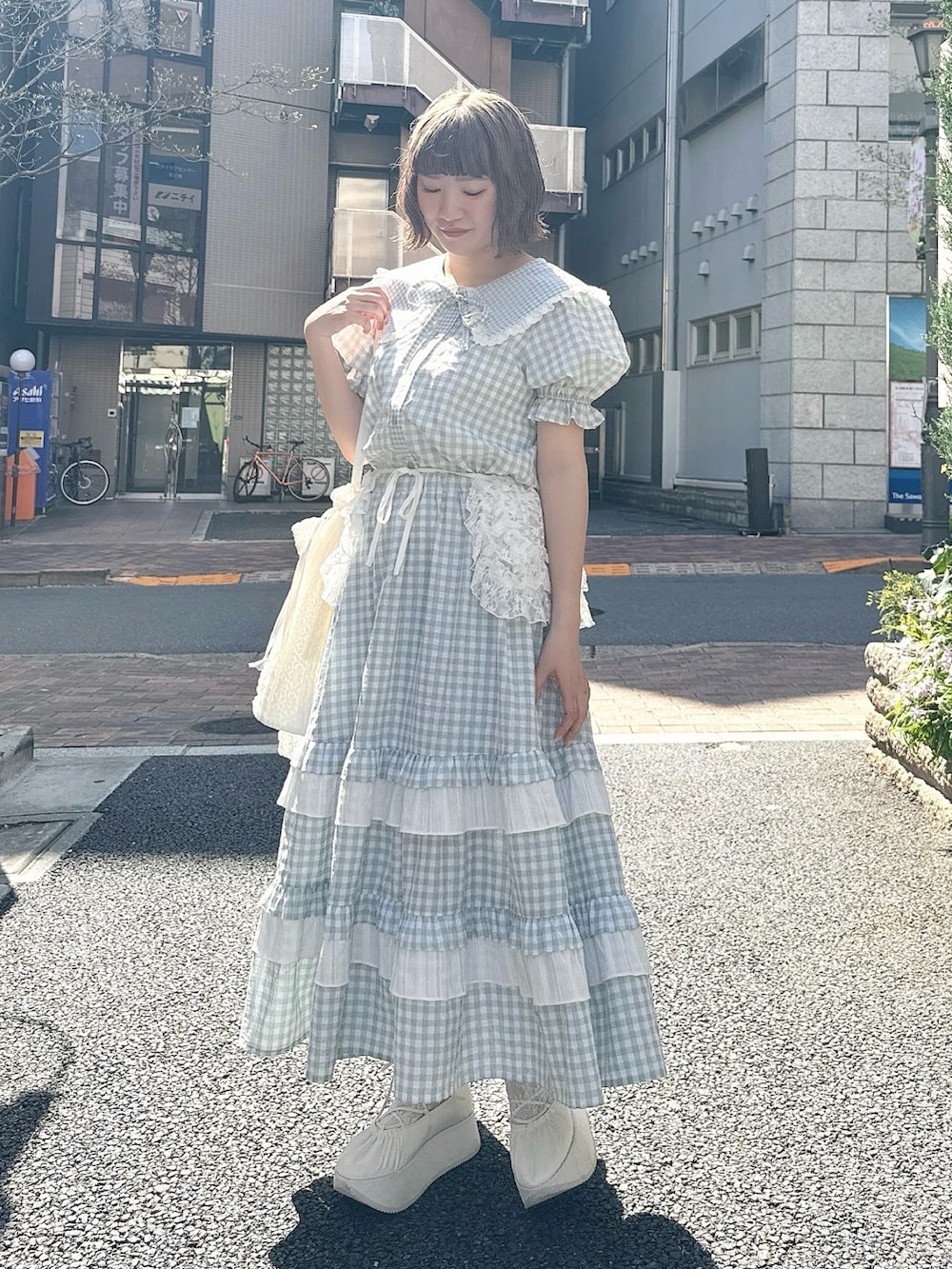 グリーン系のスカート、グリーン系のシャツ/ブラウス、ホワイト系のトートバッグを着用したレディースの春コーディネートの2枚目の写真