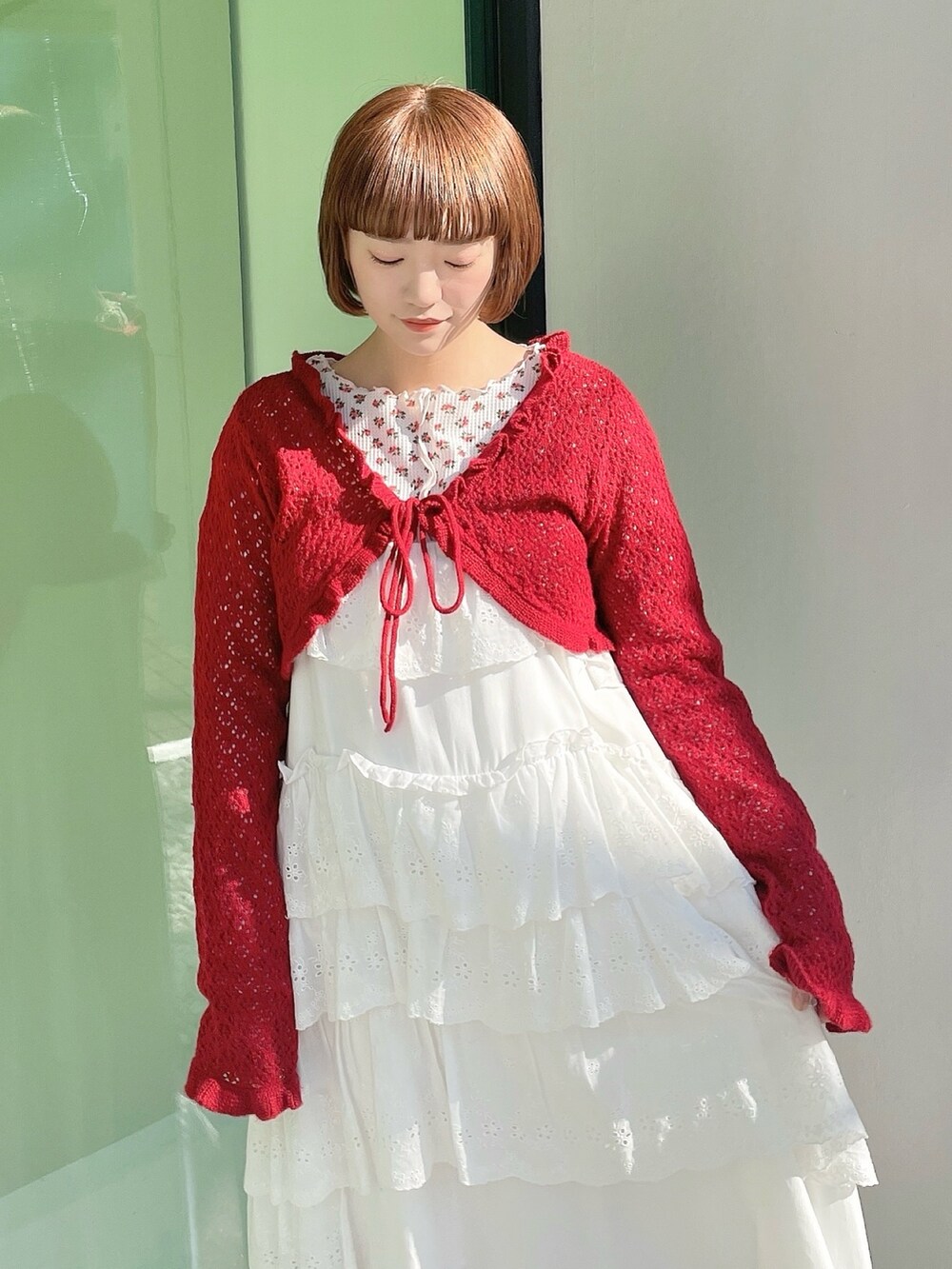 ピンク系のTシャツ/カットソー、レッド系のカーディガン/ボレロ、ホワイト系のワンピースを着用したレディースの冬コーディネートの5枚目の写真