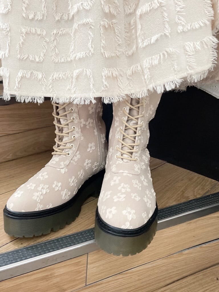 イエロー系のマウンテンパーカー、グリーン系のハンドバッグ、ベージュ系のドレスを着用したレディースの夏コーディネートの5枚目の写真