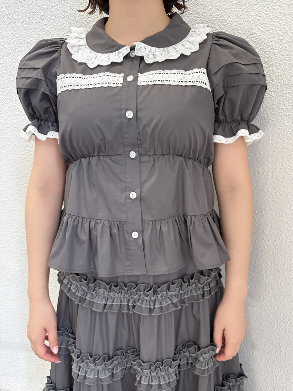 グレー系のシャツ/ブラウス、グレー系のスカート、ブラック系のスニーカーを着用したレディースの春コーディネートの5枚目の写真